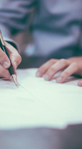 Un homme en train d'écrire sur une feuille de papier