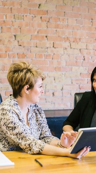 Deux femme assises à un bureau et discutant sur le thème du social et de la paie