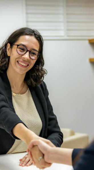 une femme serrant la main dune autre femme assise a une table