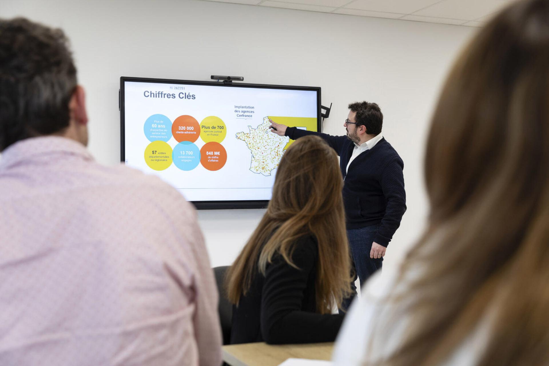 Une personne présente quelque chose sur un écran géant devant un public