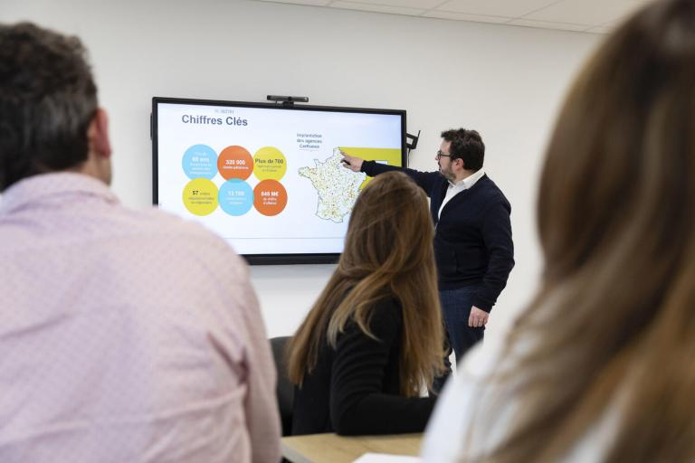 Une personne présente quelque chose sur un écran géant devant un public